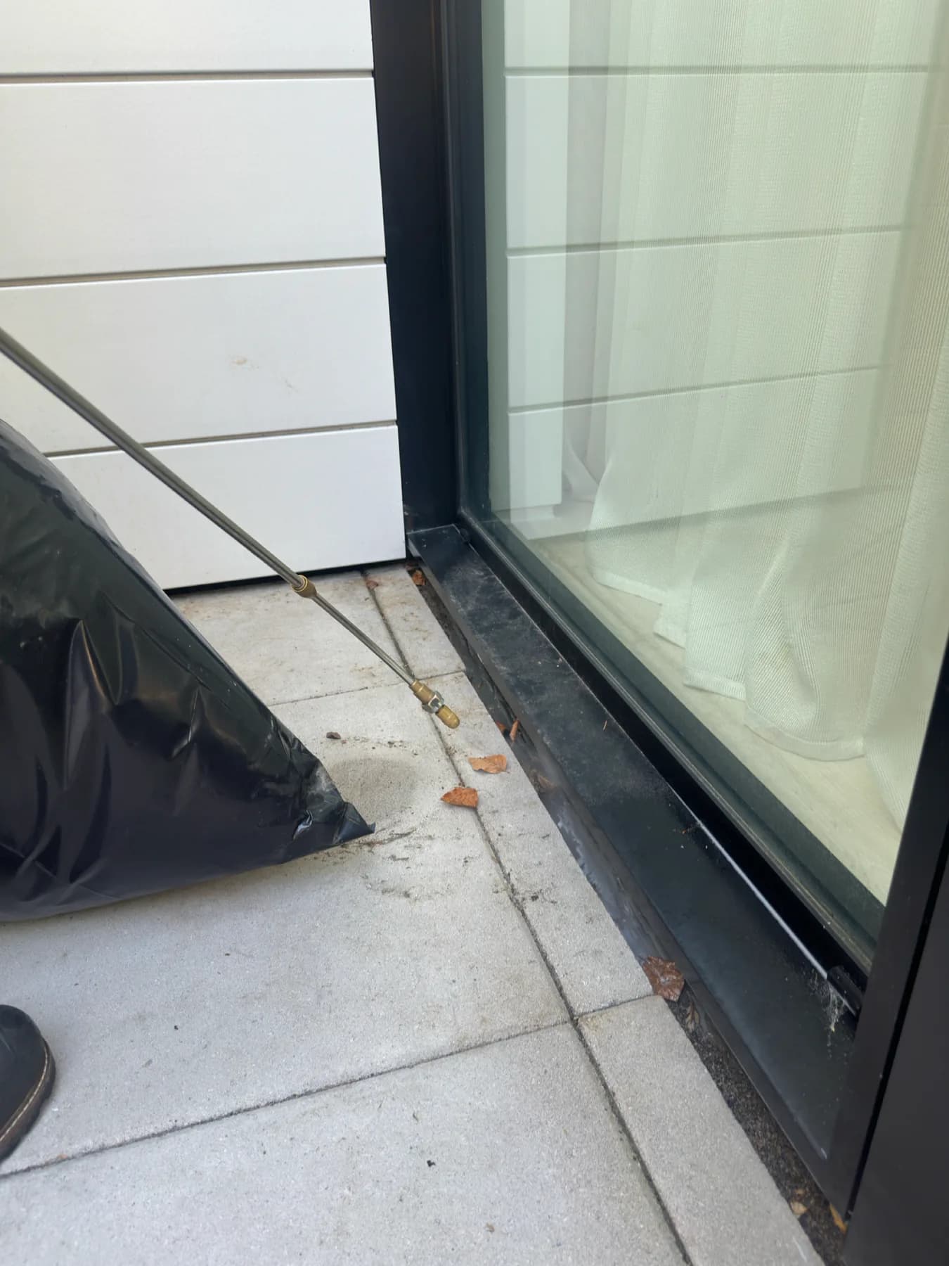 Pest-control application wand positioned along an exterior patio door track
