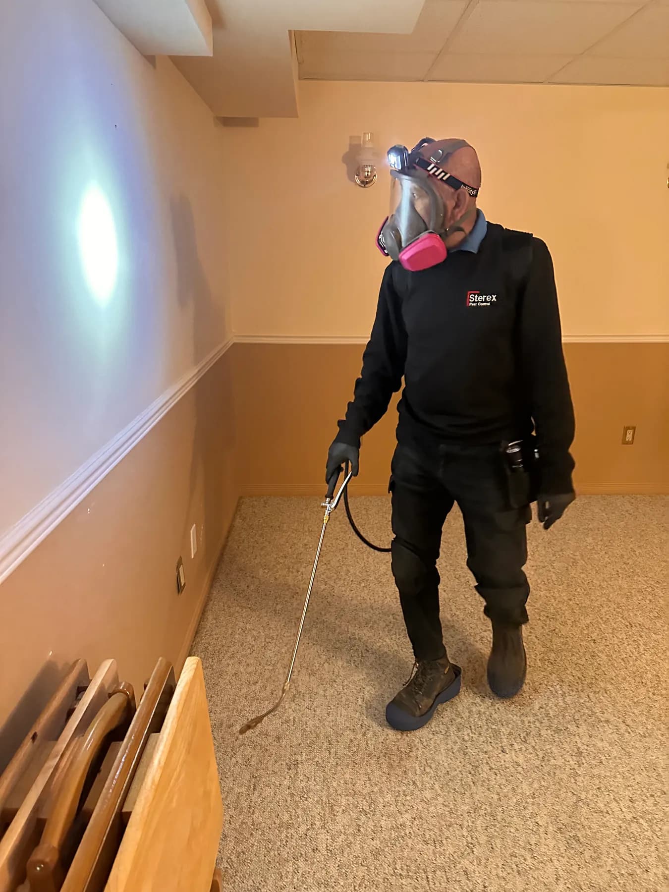 Sterex technician wearing a respirator and holding an application wand indoors