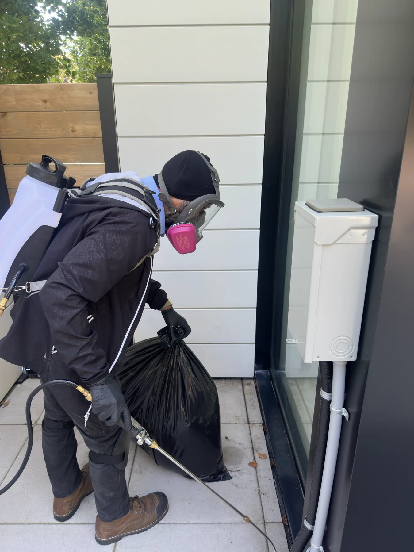 Pest control technician treating an exterior sliding-door perimeter