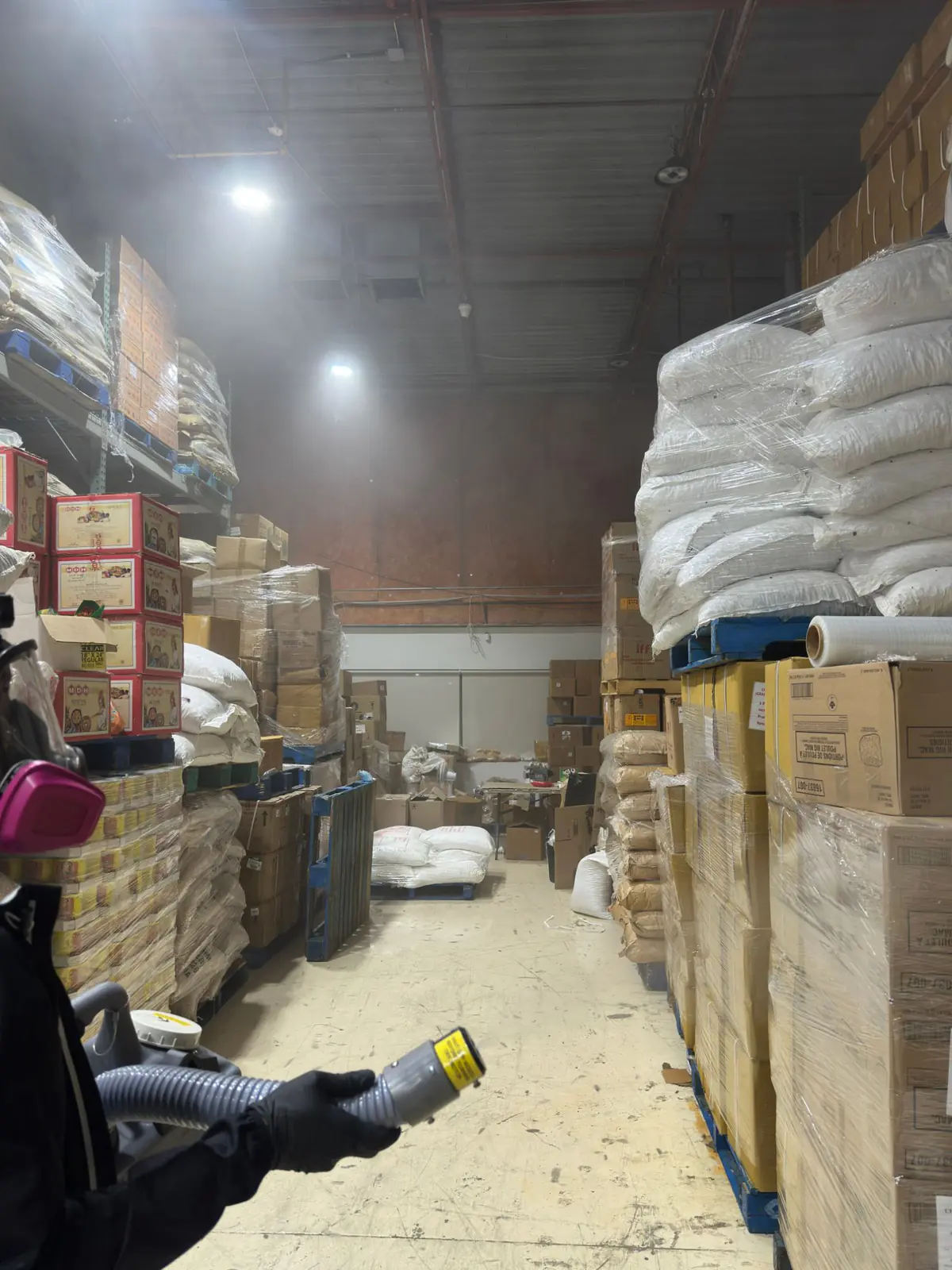 ULV fog dispersing down an aisle of palletized dry goods in a GTA food storage warehouse