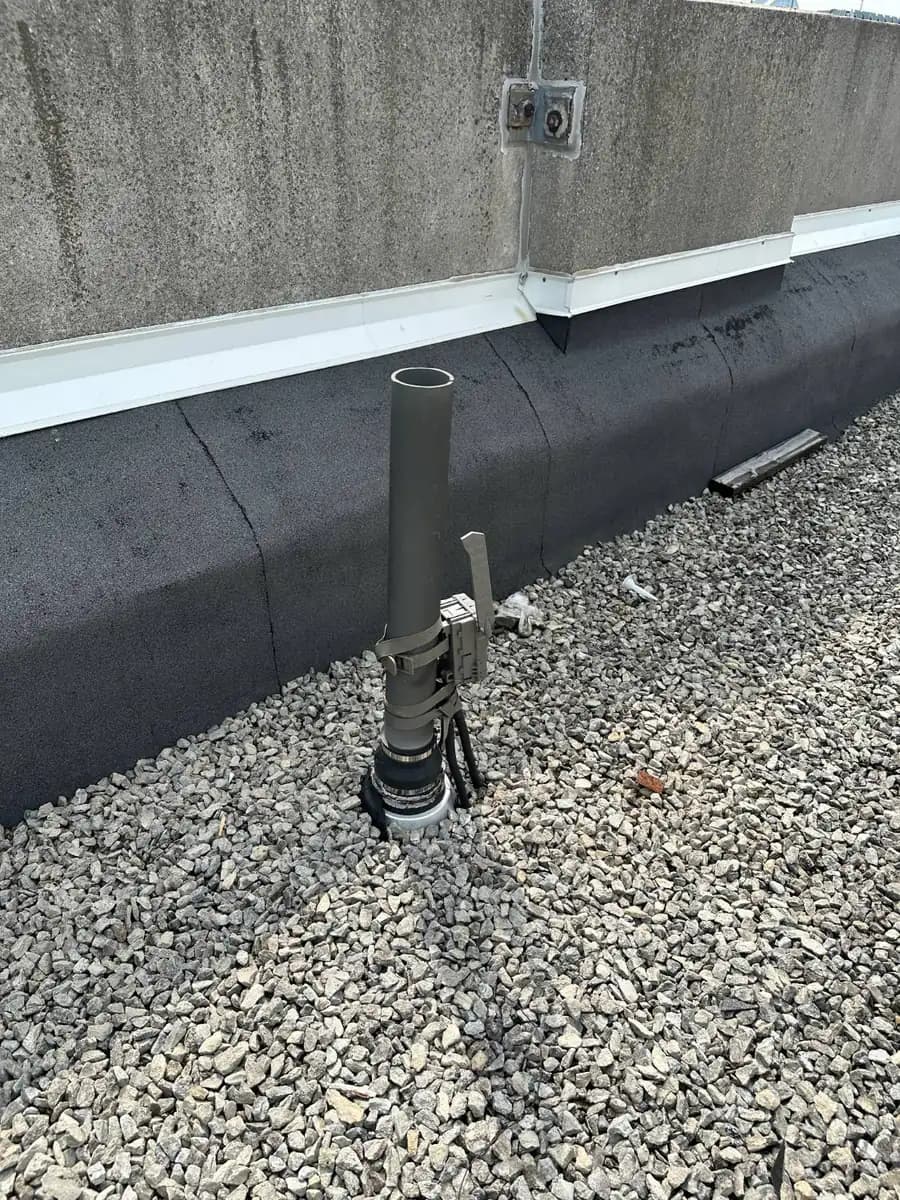 Monitoring camera strapped to a roof vent pipe pointing toward a pigeon trap