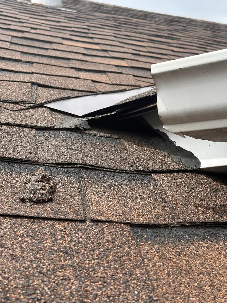 Broken roof-edge material and an open gap beside a gutter