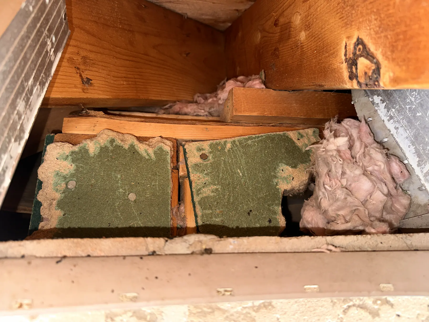 Exposed insulation boards and a dark opening inside a roof cavity